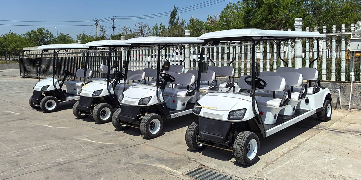 Six-seat electric golf carts parked outdoors, suitable for transporting groups of people.
