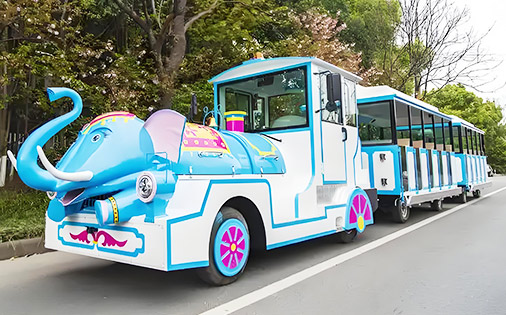Cute blue and white elephant-themed trackless train designed for amusement parks, with cheerful cartoon features and spacious passenger cars.
