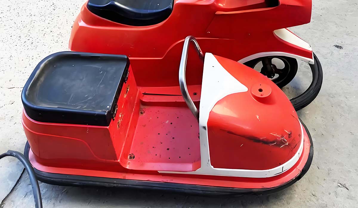 Close-up of a red bumper car in a workshop, showing the seat and structure, ready for maintenance or restoration.