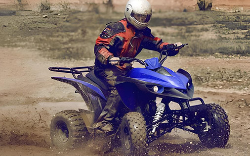 Rider enjoying a muddy ATV ride, demonstrating the off-road capability and durability of utility ATVs in challenging terrains.