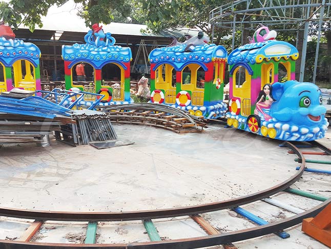 Blue sea-themed kids train ride, featuring a smiling fish locomotive and colorful ocean cars