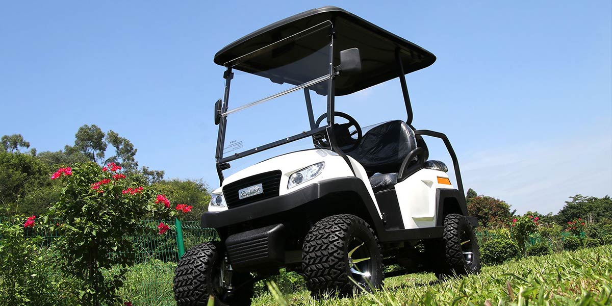White off-road electric golf cart equipped with rugged tires for all-terrain use.