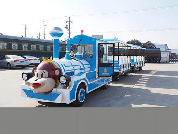 Blue cartoon-style trackless train ride with monkey face design for amusement parks.