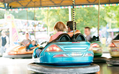 People enjoying a classic bumper car ride at an outdoor amusement park.