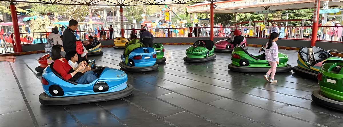 Families and kids enjoying bumper car rides at an amusement park with safe arena design